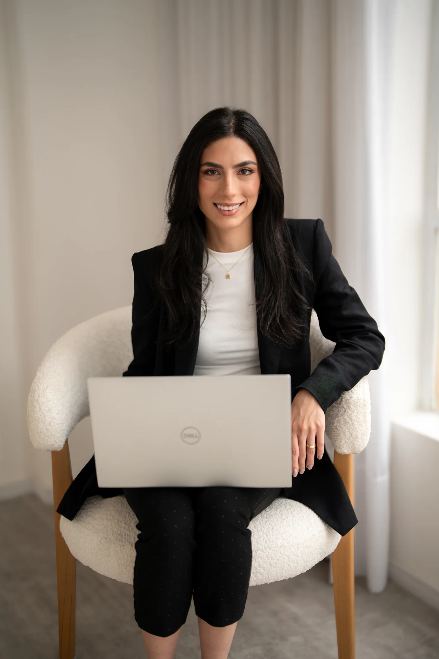 Dra. Rafaella Tacla de blazer, sentada com um notebook